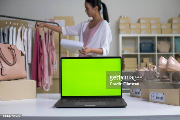laptop with blank green screen standing on the desktop in the warehouses. asian woman online seller checking stock and inventory before sending to the customer. - computer monitor green screen stock pictures, royalty-free photos & images
