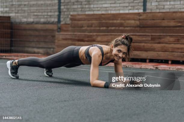 smiling active woman exercising on the sports ground outdoors. sport and healthy lifestyle concept. - postura de plancha fotografías e imágenes de stock