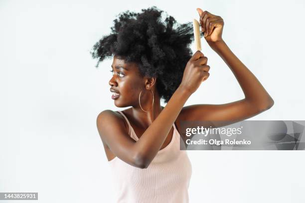 hair and skin head care. close up woman combing naughty afro hair - hair conditioner stockfoto's en -beelden