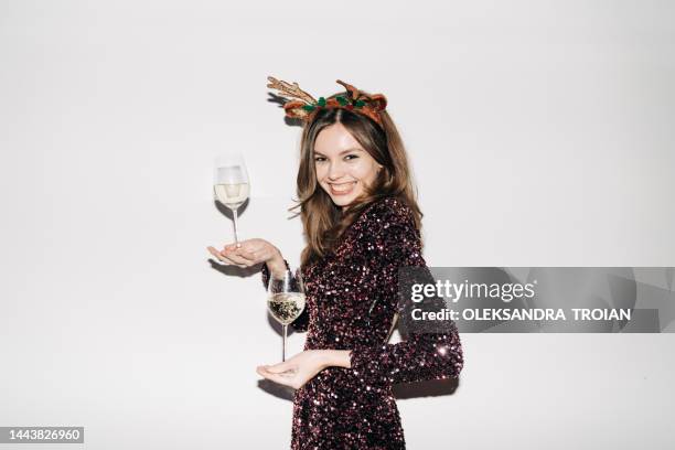 portrait with young woman with two glasses of champagne and reindeer headband (flash light) - christmas party dress stock pictures, royalty-free photos & images