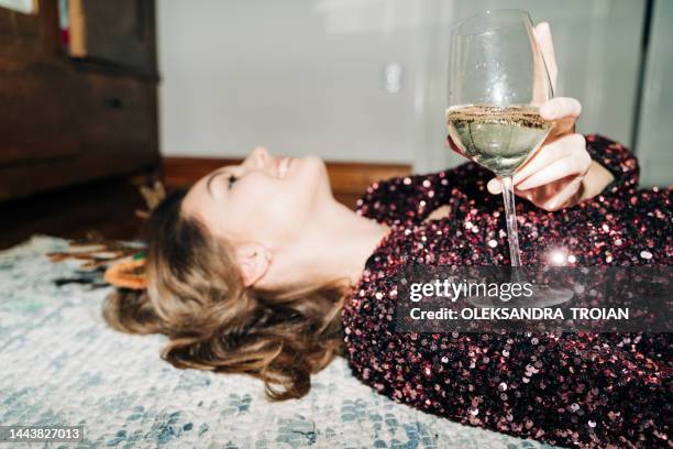 young happy woman with champagne laying on the floor, flash light, candid photo - light party ストックフォトと画像