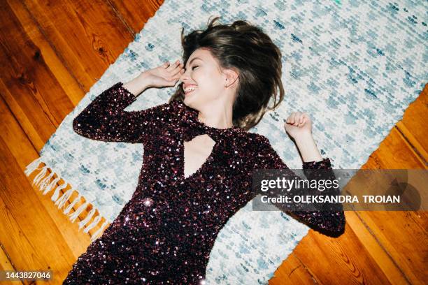 happy young woman in glittering cocktail  dress on carpet floor, flash light, user generated content - blank expression stock-fotos und bilder