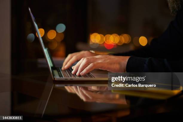 unrecognisable man working on computer at the night. close up of hands using laptop. night lights. - digitare foto e immagini stock