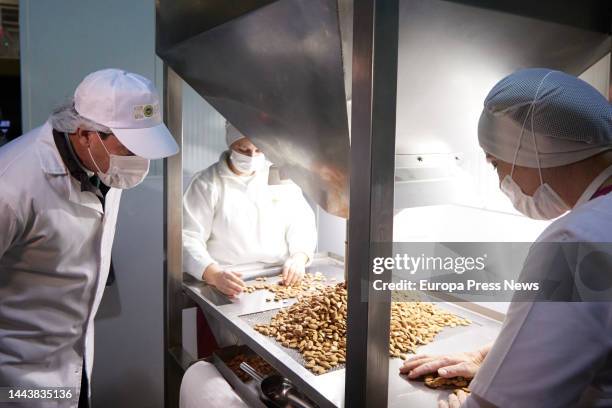 The president of the Junta de Andalucia, Juanma Moreno, observes two workers sifting almonds during the visit to the mantecados factory of the firm...