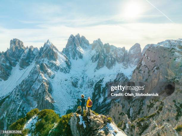 luftaufnahme von mann und frau vor dem hintergrund schneebedeckter dolomiten - dolomiti stock-fotos und bilder