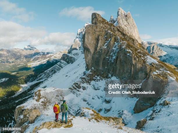 aerial view of man and woman hiking on the background of seceda mountain in winter - extreme sports point of view stock pictures, royalty-free photos & images