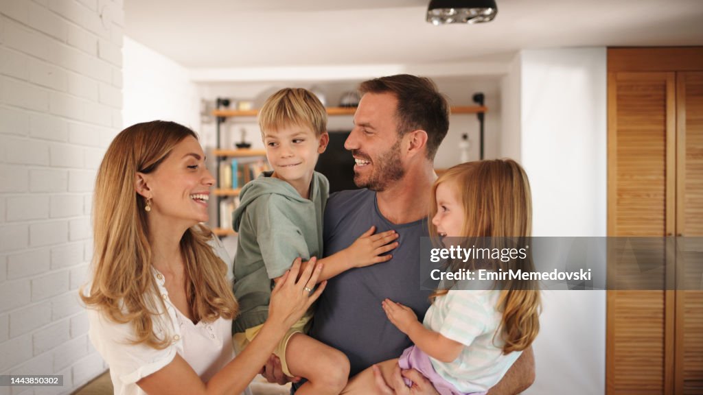 Young mom, dad and kids having a good time at home