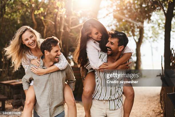 carefree couples having fun while piggybacking in spring day at the park. - piggyback stock pictures, royalty-free photos & images