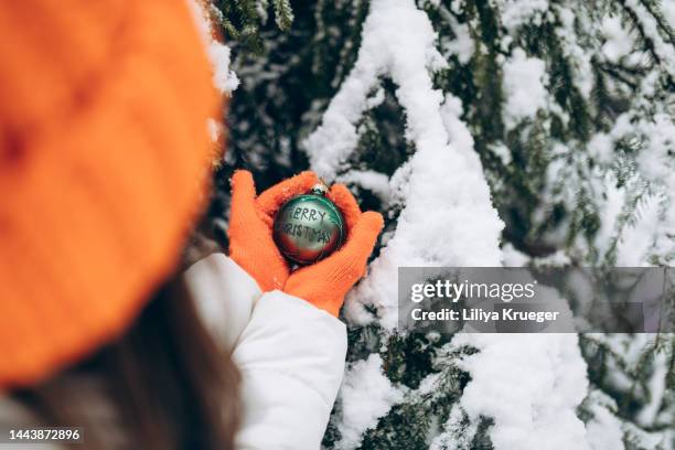 female hands with orange gloves hold christmas toy in the winter forest. - mid winter ball imagens e fotografias de stock