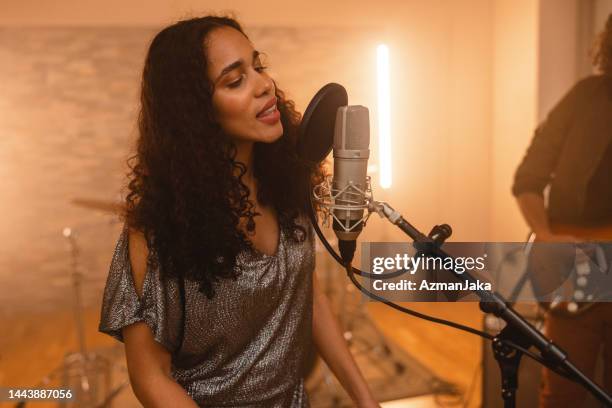 young adult black female music artist singing in a warm music studio - pop music stock pictures, royalty-free photos & images