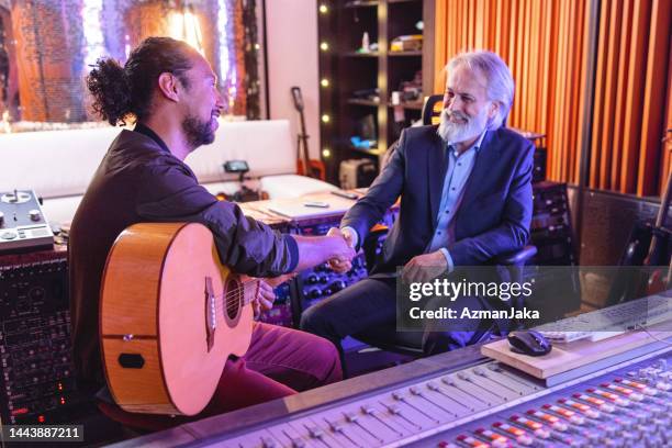 black male musician shaking hands with a senior caucasian producer in a music studio - professional musician stock pictures, royalty-free photos & images