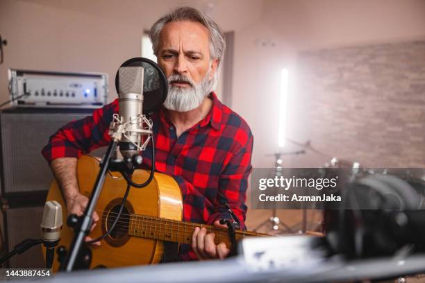 senior adult caucasian male rock singer playing a guitar and singing in a beautiful recording studio - male musician stock pictures, royalty-free photos & images