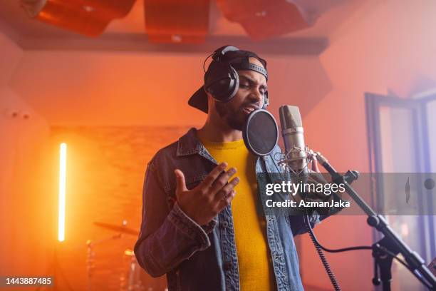 young adult black male music singer passionately singing in a beautiful illuminated studio - rapper stockfoto's en -beelden