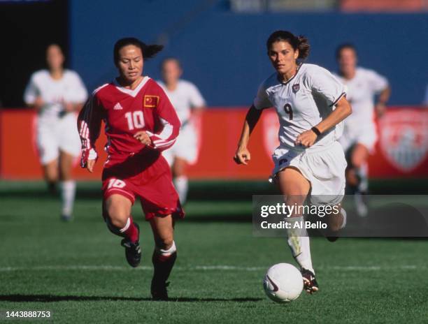 Mia Hamm, Forward for the United States in motion with the football running past Liu Ailing, Midfielder for China during their FIFA Women's...