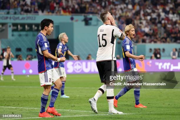 Japan players celebrate the 2-1 win while Niklas Suele of Germany shows dejection after the FIFA World Cup Qatar 2022 Group E match between Germany...