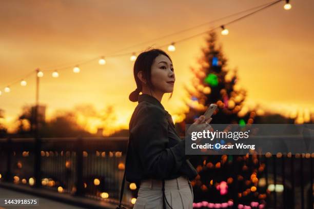 businesswoman using mobile phone and walking through city street in christmas season - christmas decorations in store stock pictures, royalty-free photos & images