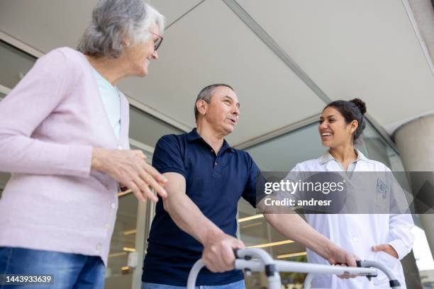 happy doctor talking to a patient at the door as he leaves the hospital - demobbed stock pictures, royalty-free photos & images