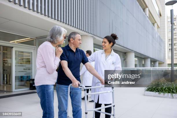 doctor looking happy to see her patient walking with a walker at the hospital - demobbed stock pictures, royalty-free photos & images