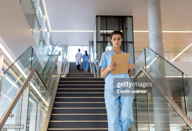 nurse reading a medical chart while walking down the stairs at a hospital - doctor looking down stock pictures, royalty-free photos & images