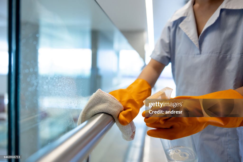 Nahaufnahme einer Reinigungskraft, die in einem Krankenhaus arbeitet und einen Handlauf reinigt