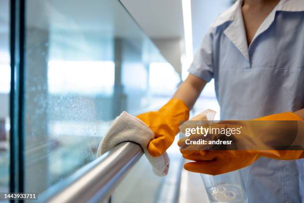 nahaufnahme einer reinigungskraft, die in einem krankenhaus arbeitet und einen handlauf reinigt - putzfrau stock-fotos und bilder