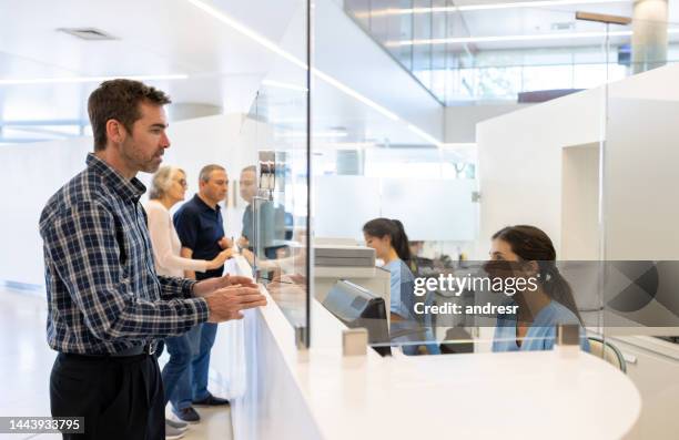man registering at the hospital but complaining to the receptionist - registry office stock pictures, royalty-free photos & images