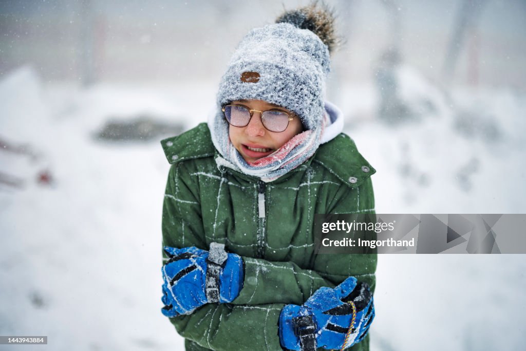 Portrait of a teenage boy who is very cold during the blizzard on a winter day