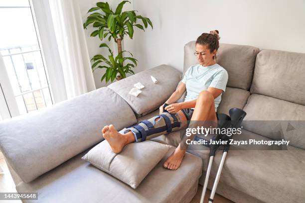 woman healing her leg at home after knee surgery - muleta fotografías e imágenes de stock