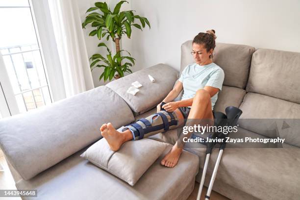 woman healing her leg at home after knee surgery - leg wound stockfoto's en -beelden