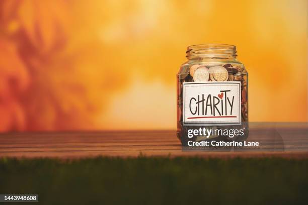 charity jar filled with american currency with a warm autumnal background. donation concept with copy space - gratitude jar stock pictures, royalty-free photos & images