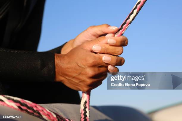 close up female surfer's hands holding surfboard leash - extreme close up fotografías e imágenes de stock