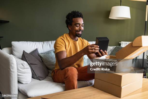smiling man opening a delivery box - open parcel stock pictures, royalty-free photos & images