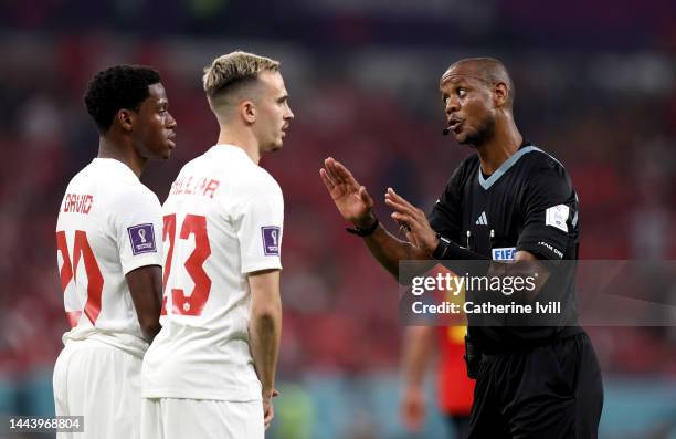 Referee Janny Sikazwe speaks to Jonathan David and Liam Millar of Canada during the FIFA World Cup Qatar 2022 Group F match between Belgium and...