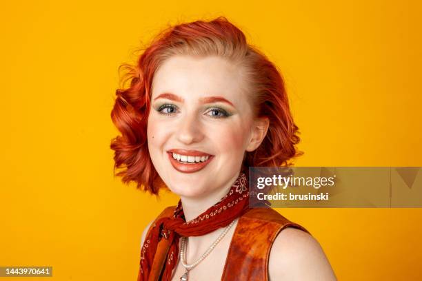 close-up studio portrait of a young red-haired white woman dressed in retro style against a yellow background - bobbed hair stock pictures, royalty-free photos & images
