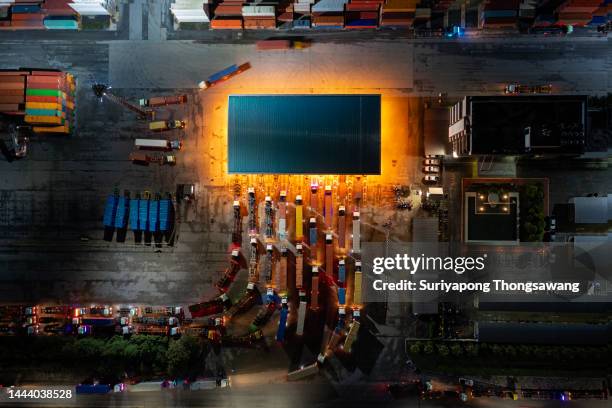 aerial top view container trucks line up to enter the terminal for unload container to container cargo ship at terminal commercial port at dusk, business logistics import export or freight transportation. - shipyard aerial stock pictures, royalty-free photos & images