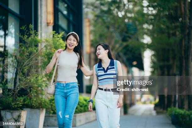 smiling friends in discussion while walking through town during vacation - community arm in arm stock pictures, royalty-free photos & images