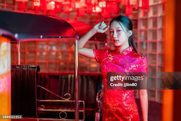 Studio portrait photo of a beautiful young asian female lady model wearing elegant red traditional chinese dress cheongsam costume with cool emotion look standing beside a tuk tuk taxi vehicle studio portrait photo beautiful young asian