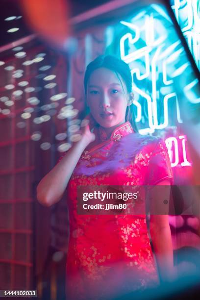 Studio portrait photo of a beautiful young asian female lady model wearing elegant red traditional chinese dress cheongsam costume with cool emotion look standing beside a tuk tuk taxi vehicle studio portrait photo beautiful young asian