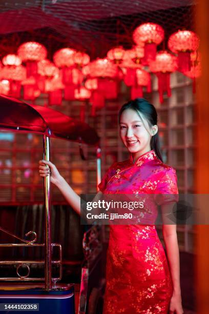 Studio portrait photo of a beautiful young asian female lady model wearing elegant red traditional chinese dress cheongsam costume with cool emotion look standing beside a tuk tuk taxi vehicle studio portrait photo beautiful young asian