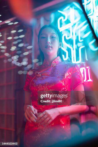 Studio portrait photo of a beautiful young asian female lady model wearing elegant red traditional chinese dress cheongsam costume with cool emotion look standing beside a tuk tuk taxi vehicle studio portrait photo beautiful young asian