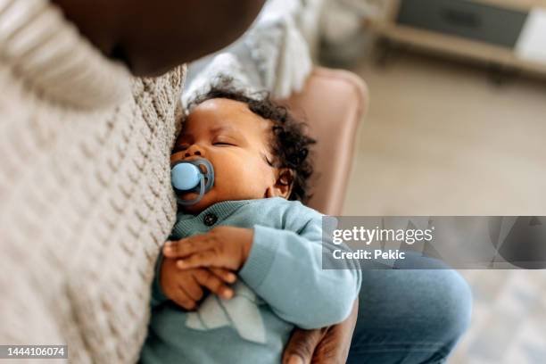 close up of a sleeping baby in mother's arms - pacifier stockfoto's en -beelden