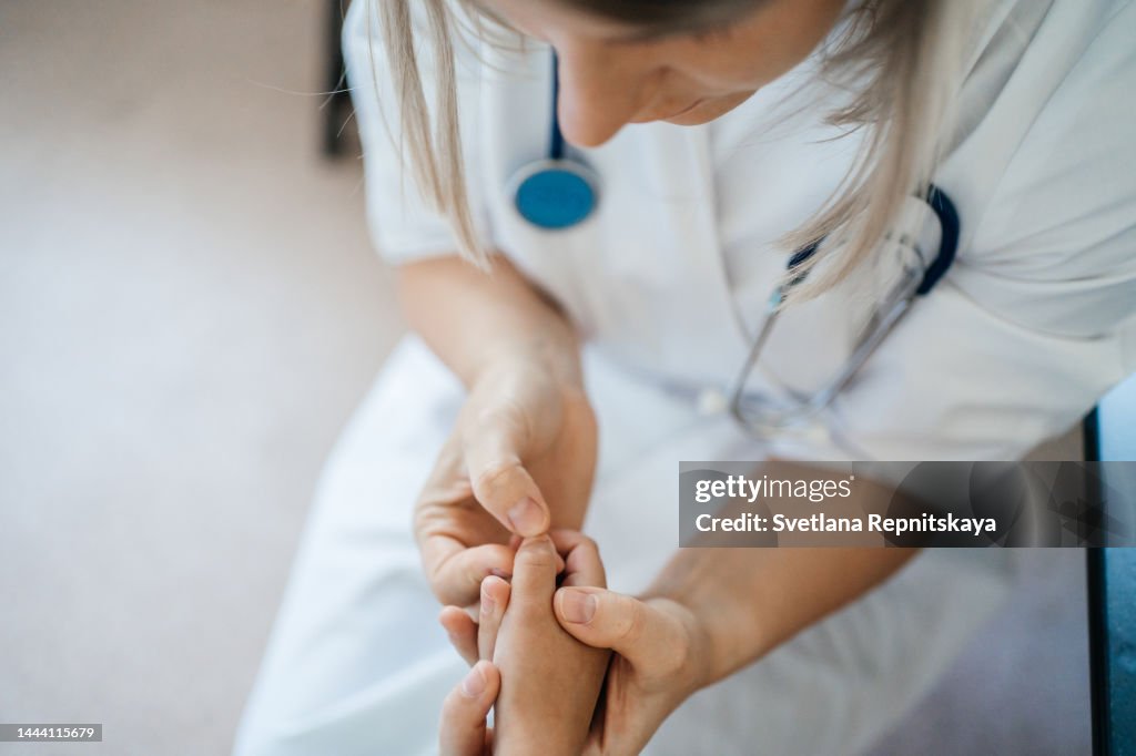 Woman pediatrician examines sick hands of a child