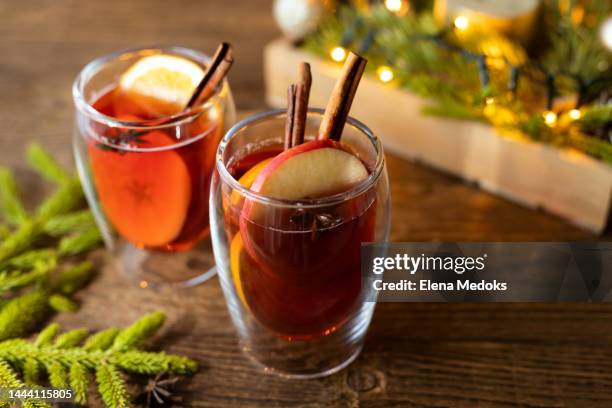 glasses of hot winter mulled wine with cinnamon sticks and cloves on a wooden table - mulled wine stock pictures, royalty-free photos & images