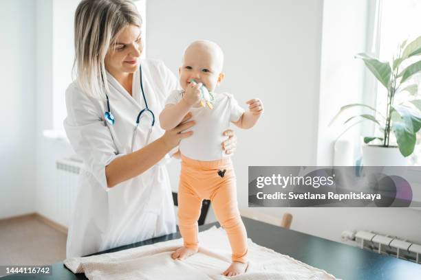 woman doctor pediatrician carefully examines baby in clinic - womans clinic heart stockfoto's en -beelden