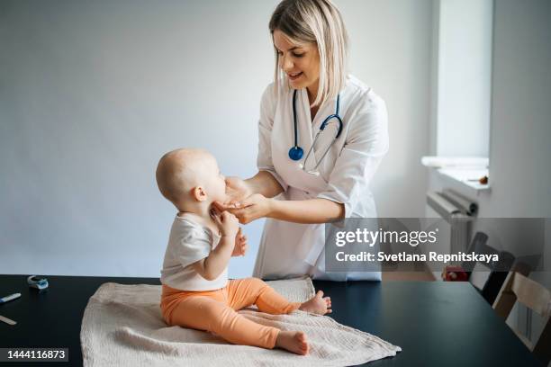 woman doctor pediatrician with a smile examines the baby in the clinic - doctor and baby stockfoto's en -beelden