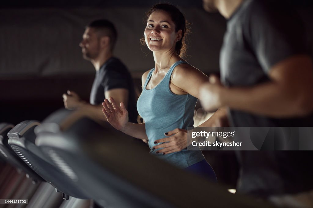 Glückliche athletische Frau beim Aufwärmen auf dem Laufband in einem Fitnessstudio.