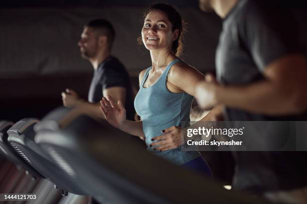 happy athletic woman warming up on treadmill in a gym. - healthclub stockfoto's en -beelden