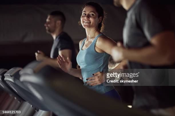 mulher atlética feliz aquecendo na esteira em uma academia. - academia de ginástica - fotografias e filmes do acervo
