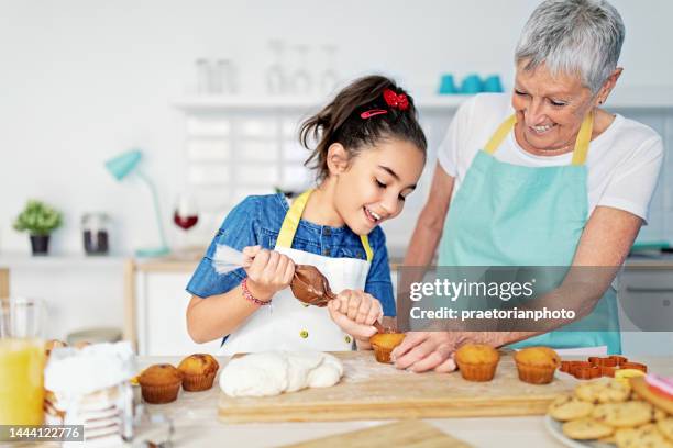 großmutter und enkelin kochen gemeinsam in der küche - child loves chocolates stock-fotos und bilder