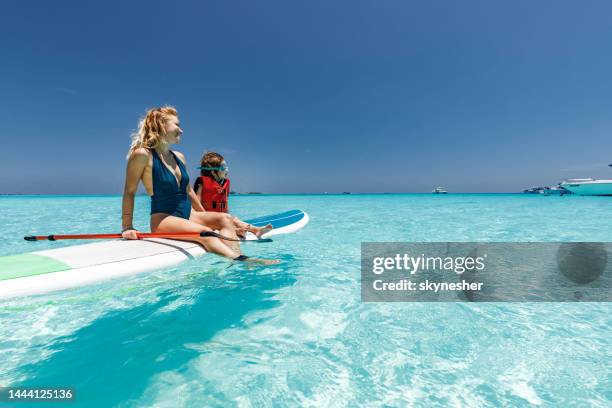 happy single mother and son sitting on paddleboard at sea. - maldives sport stock pictures, royalty-free photos & images